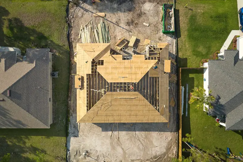 Aerial view of a house under construction with its wooden roof frame in place